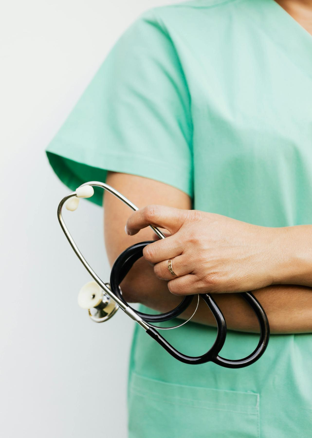 A nurse in green scrubs holding a stethoscope